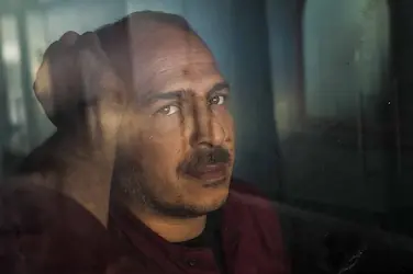 Homme pensif derrière une vitre, illustrant l'isolement et la tristesse liés à la dépression