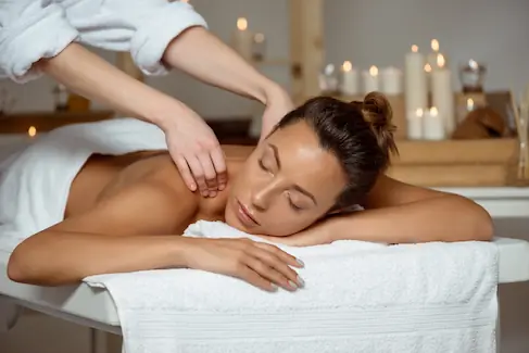Femme allongée recevant un massage bien-être sur table, dans une ambiance apaisante et lumineuse