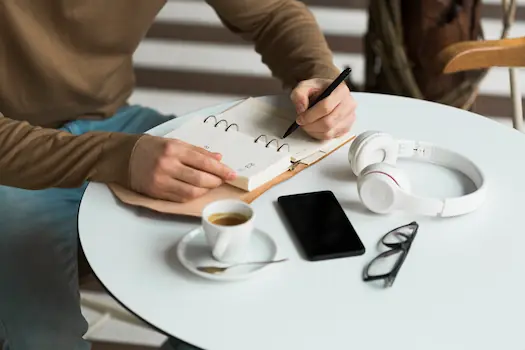 Personne prenant des notes dans un carnet lors d'un accompagnement naturopathique, illustration de la mise en action progressive