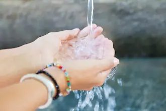 Mains en coupe recevant un filet d'eau vive, illustrant l'usage thérapeutique de l'eau en naturopathie